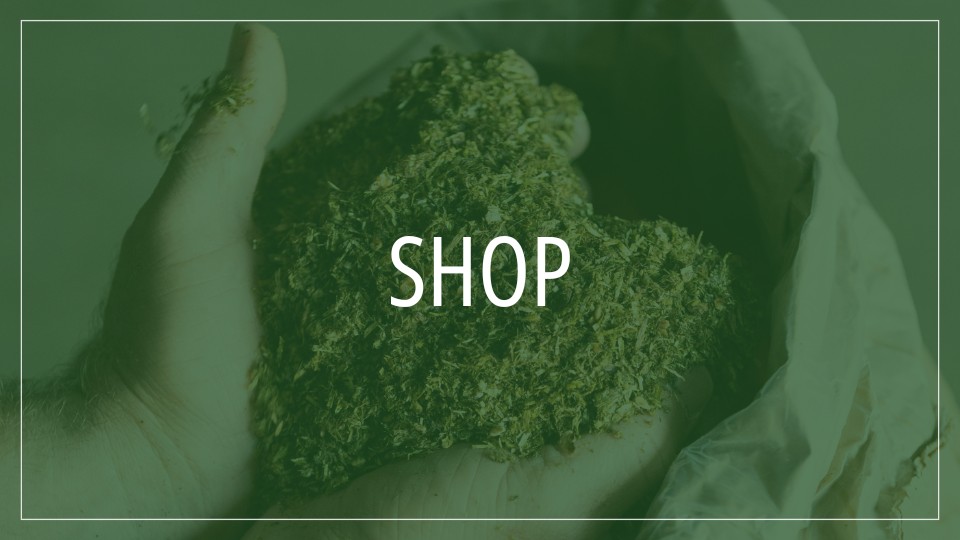Hände halten eine große Menge Pferdefutter das  ein Herz bildet mit dem Text "Shop" darüber.