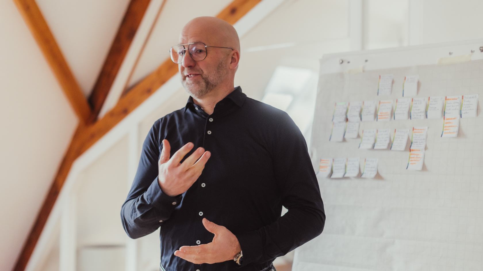 Consulting und Coaching von Heiner Beifuss bei HBD Agrar Coach Heiner Beifuss mit Brille und blauem Hemd hält eine Präsentation vor einem Flipchart mit vielen Notizzetteln.