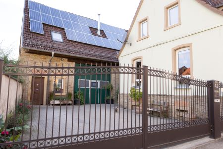 HBD Büro mit Solarzellen und Metalltor Ein Haus mit Solarzellen auf dem Dach und einem Metalltor im Vordergrund.